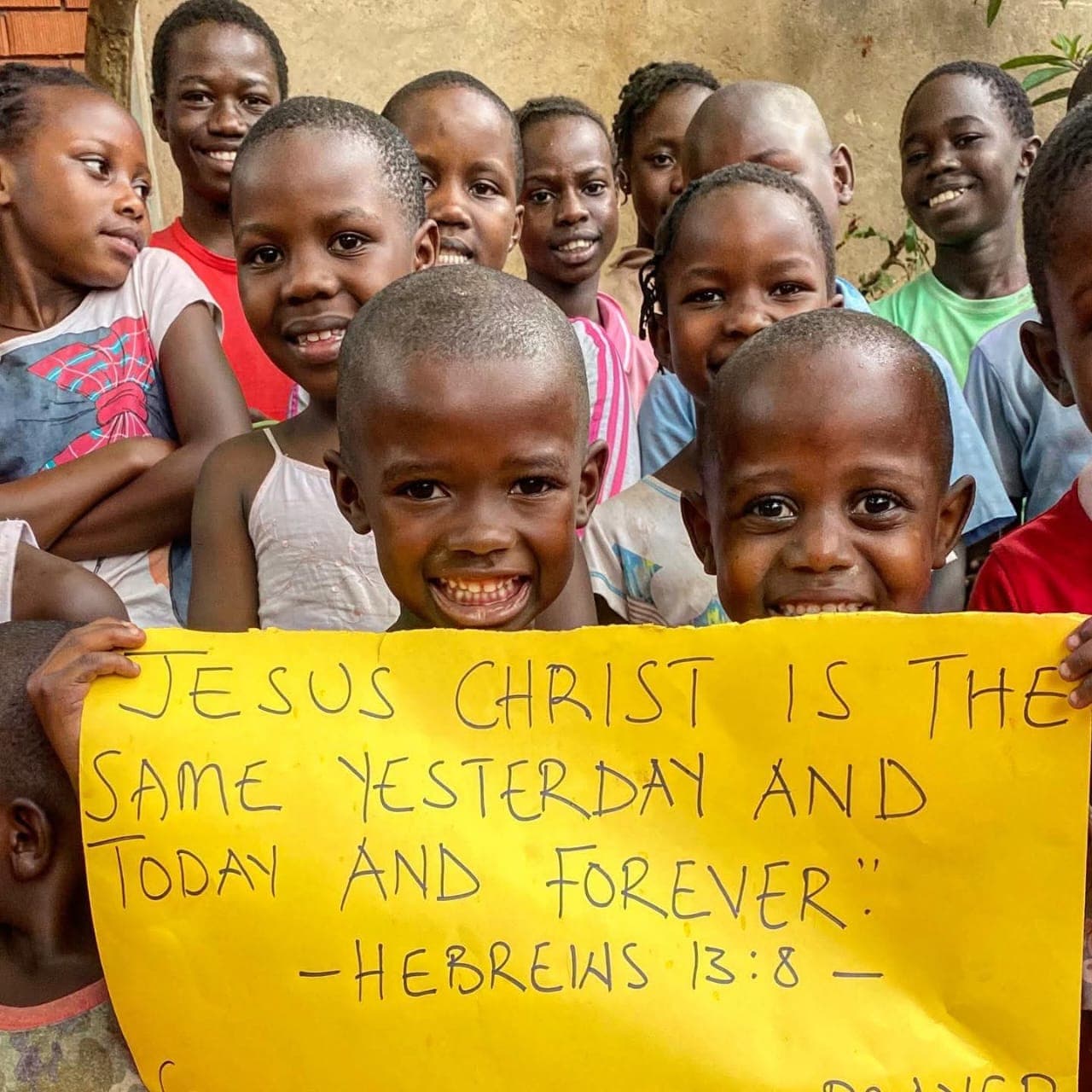 Children holding a Scripture sign as part of faith guidance at Army of God Children's Charity